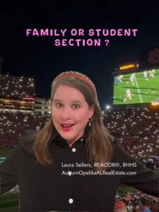 Auburn football fans in the student section cheering under orange and blue lights.