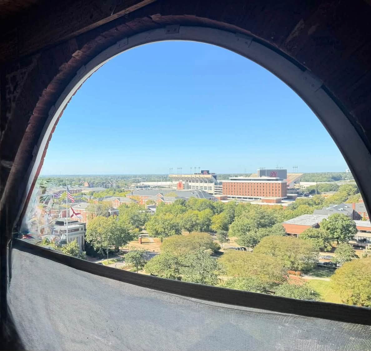 Auburn University campus and Jordan-Hare Stadium seen through an arched window in Samford Hall's tower