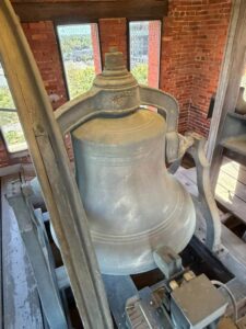 Large metal bell and support frame inside Samford Hall's brick bell tower at Auburn University